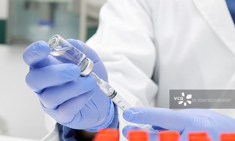 医护人员用注射器从药瓶中抽取澄清液体图片素材