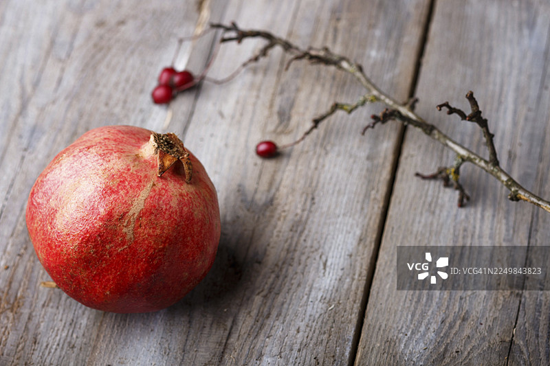 成熟的石榴和一根树枝放在质朴的木质背景上图片素材