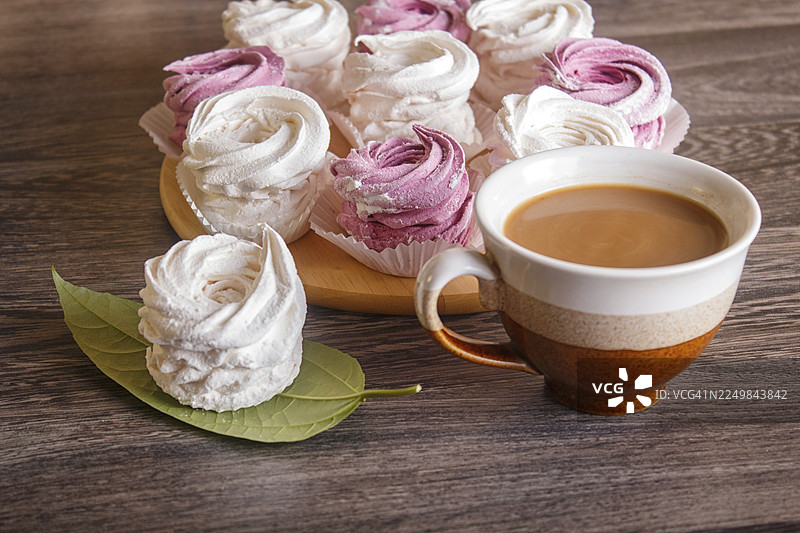 粉白色自制棉花糖（如泽菲糖）摆放在圆木板上，背景为灰色木纹图片素材