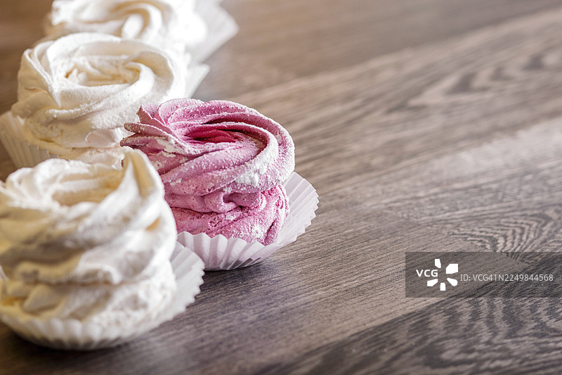 粉白色手工棉花糖，置于灰色木质背景上，焦点选择性拍摄图片素材