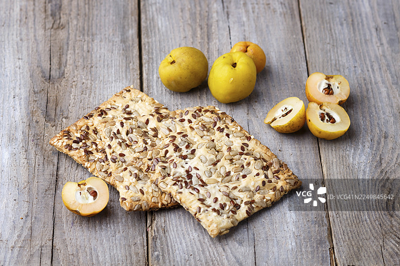 亚麻籽、芝麻和葵花籽饼干，搭配乡村木质背景上的黄色榅桲水果图片素材