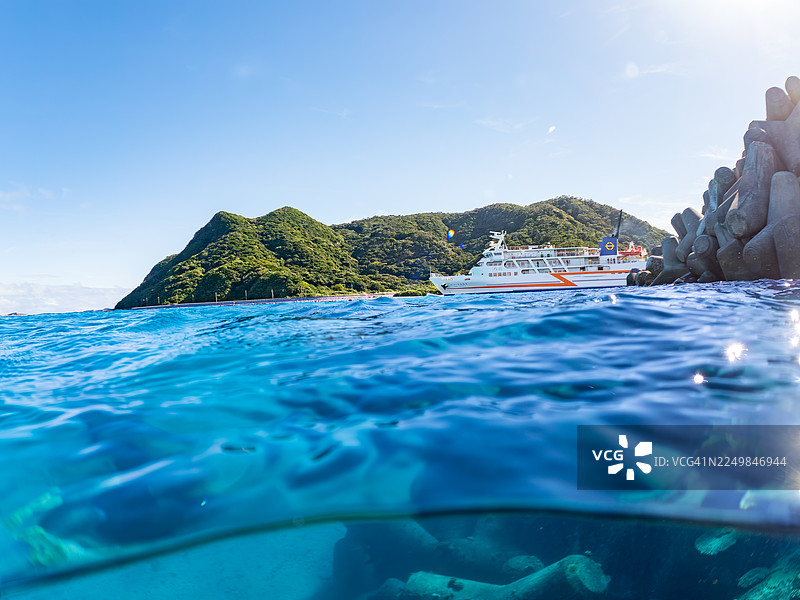 从奇妙的珊瑚礁水面拍摄的渡嘉敷岛渡轮“座间味号”和古座间岛的美丽水上镜头。成群的热带鱼。美丽的珊瑚礁和游泳的人们。阿嘉海滩，阿嘉岛，冲绳，庆良间图片素材