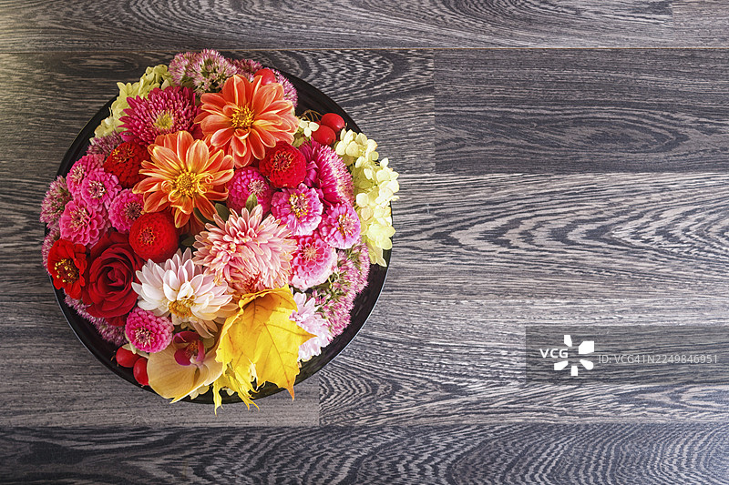 盘子上的秋季花卉插花。大丽花、百日草、玫瑰、兰花、枫叶。复制空间图片素材