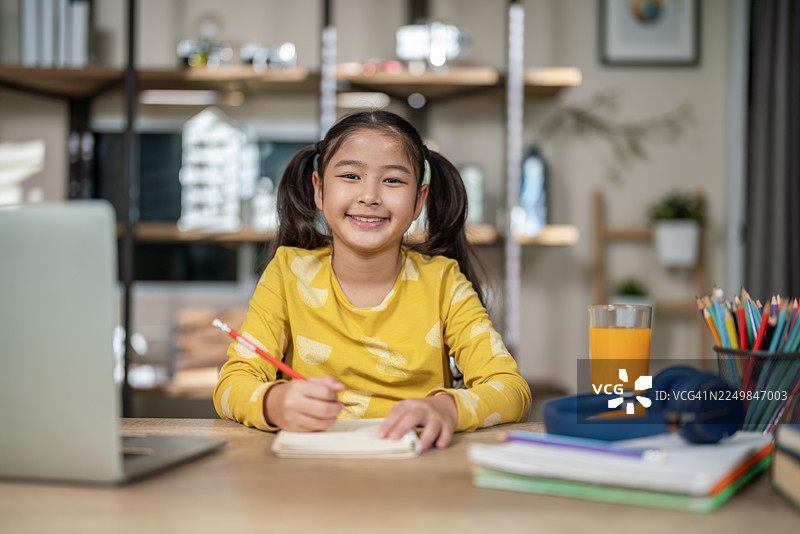 小女孩在家通过在线教育学习并微笑图片素材