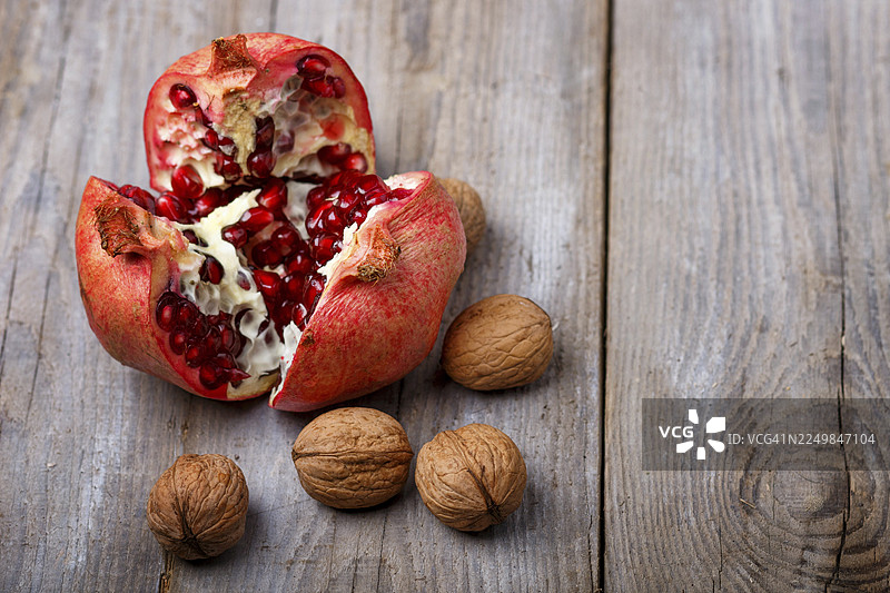 成熟的石榴和核桃放在乡村木质背景上图片素材