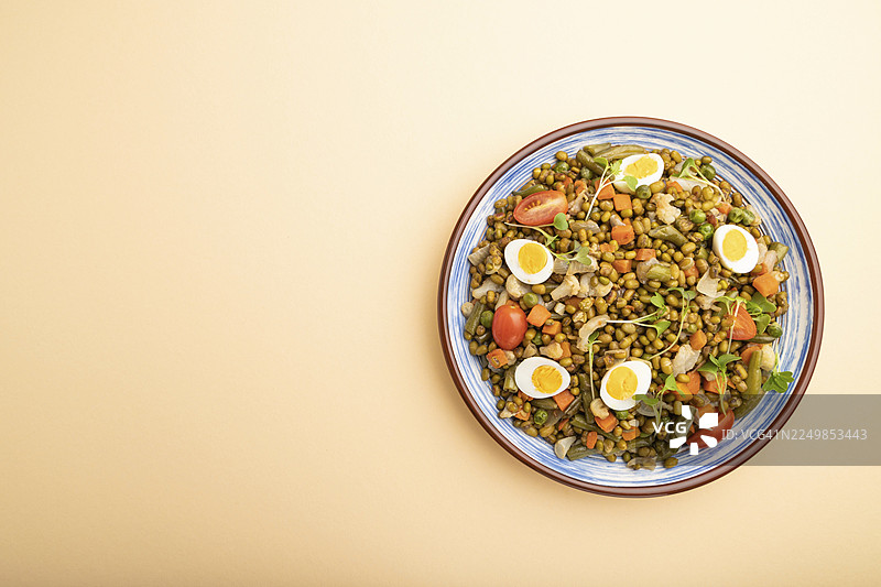 粉橙色背景上的绿豆粥，配有鹌鹑蛋、番茄和微型蔬菜苗。俯视，平铺，可留白。图片素材