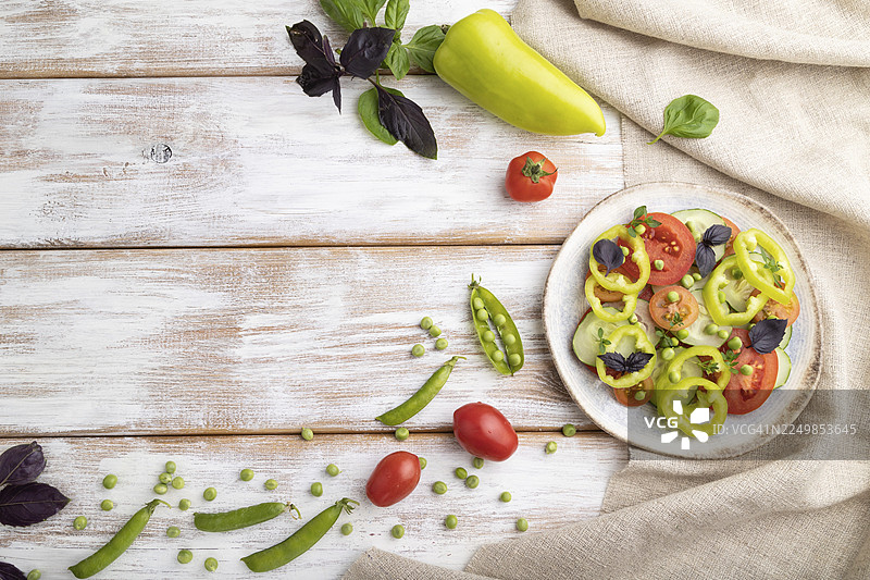 绿豌豆、番茄、辣椒和罗勒制成的素食沙拉，摆放在白色木质背景和亚麻布上。俯视视角，留有复制空间，平面图。图片素材