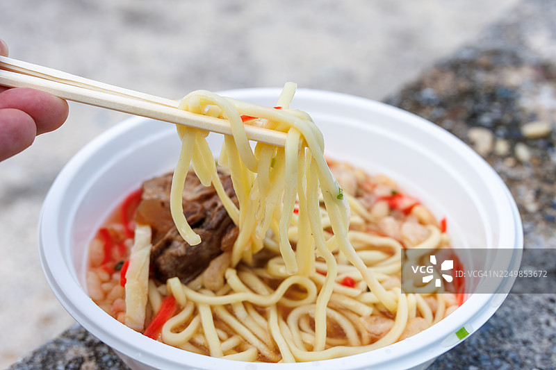 早餐享用一大碗冲绳荞麦面。面上铺满了软嫩入味的炖猪肋排(Sōki)。搭配一杯三线茶(冲绳风味茉莉花茶)。地点:冲绳岛座间味港。一个如同热带天堂般的离岛。图片素材