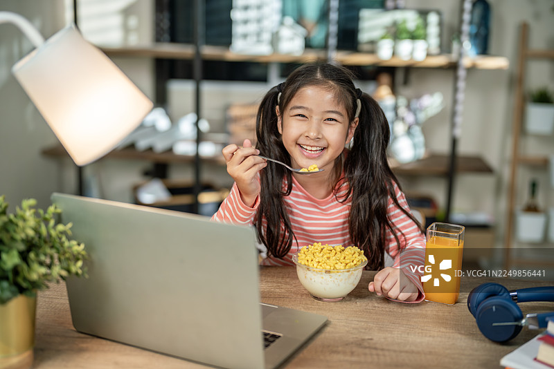 亚洲女孩在家在线学习时吃麦片图片素材