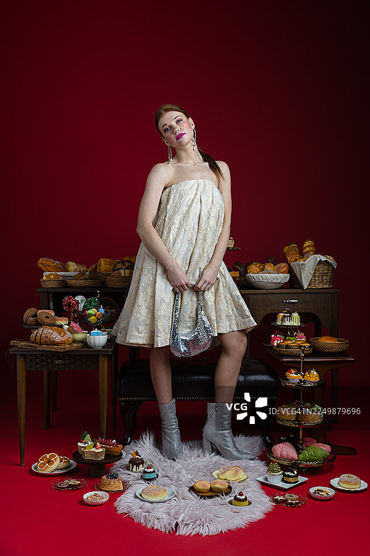 优雅的女士被奢华的糕点和美食环绕图片素材