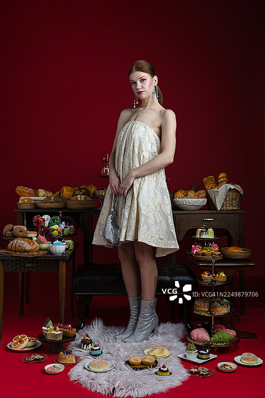 优雅的女士被奢华的糕点和美食包围图片素材