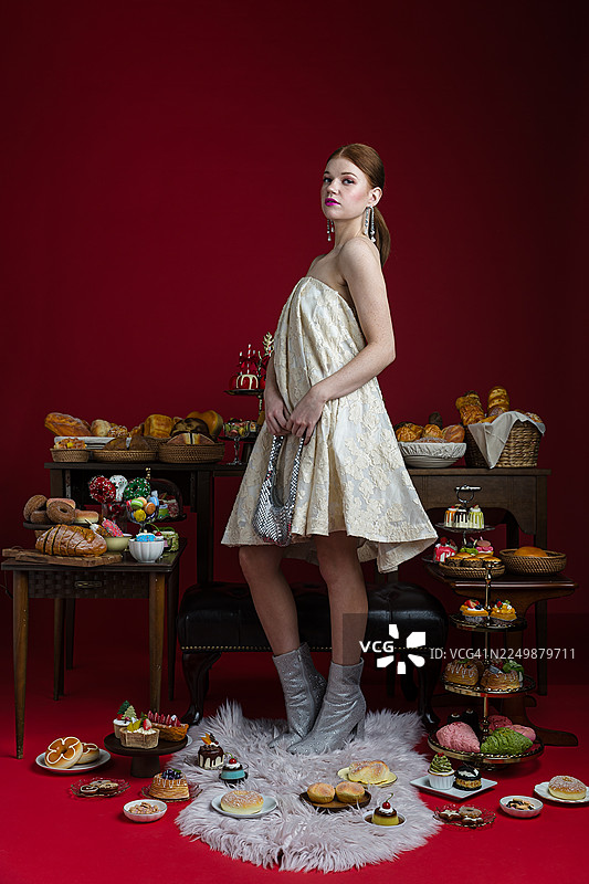 优雅的女士被奢华的糕点和美食环绕图片素材
