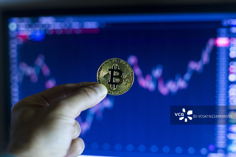 一只手握着一枚金色的比特币图片素材