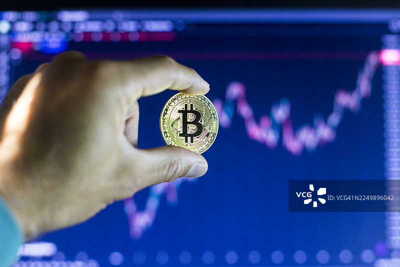 一只手握着一枚金色的比特币图片素材