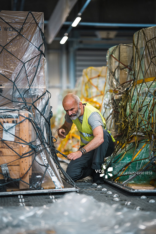 专注表情的成熟男性工人在机场仓库整理货物图片素材