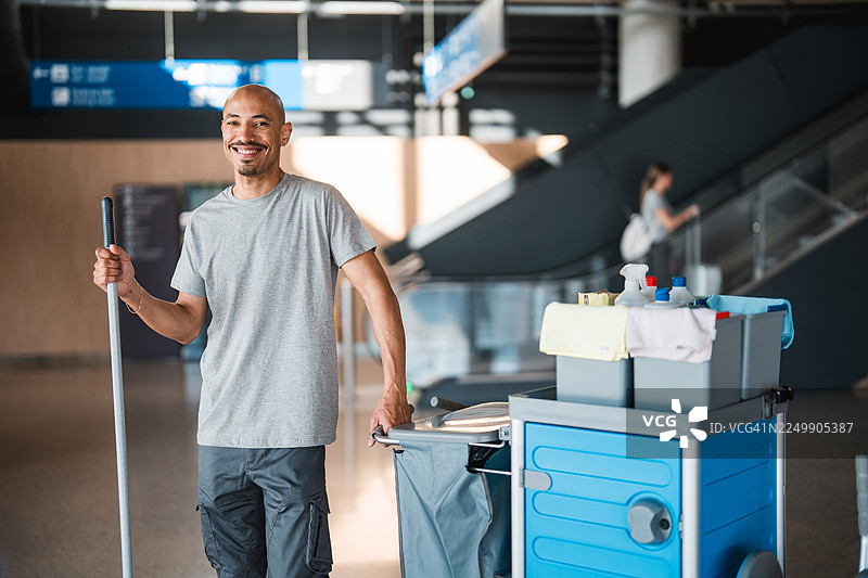 中年拉丁裔机场清洁工在现代航站楼内使用清洁车工作图片素材