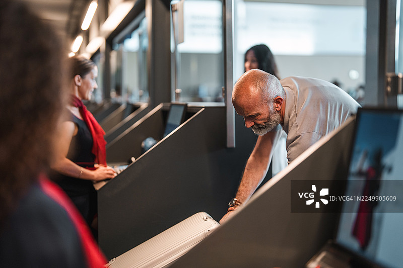 亚洲航空工作人员在值机柜台协助一位年长的高加索男性处理行李图片素材
