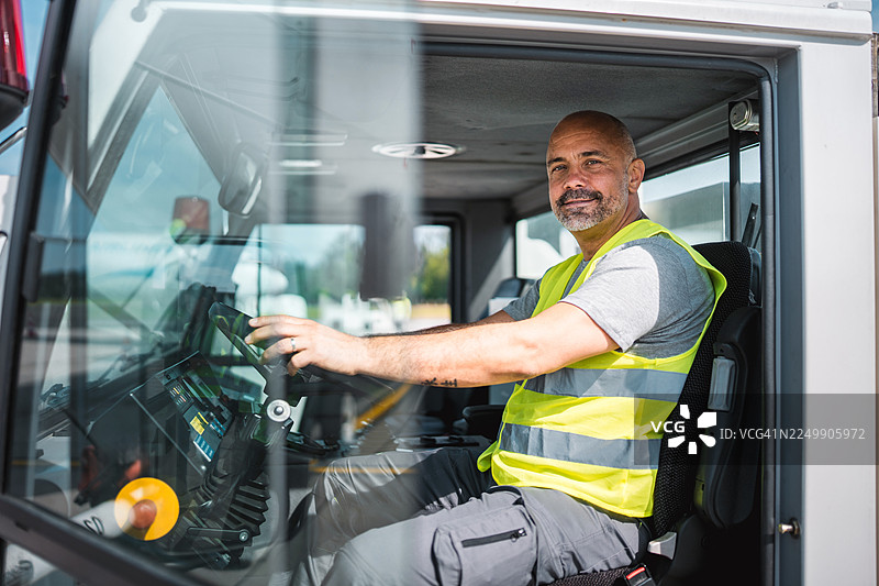 穿着高可见度背心的牵引车司机坐在驾驶室内图片素材
