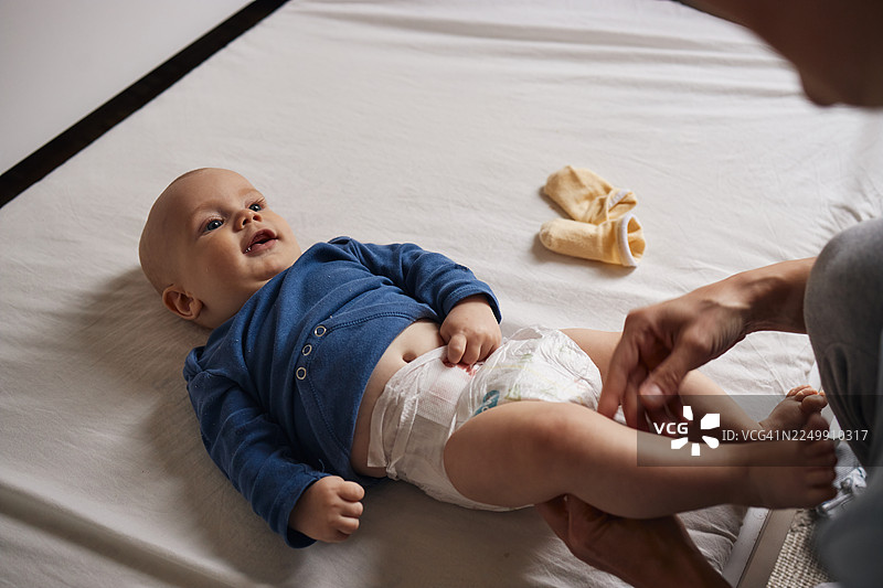 父母在床上为开心的宝宝更换尿布图片素材