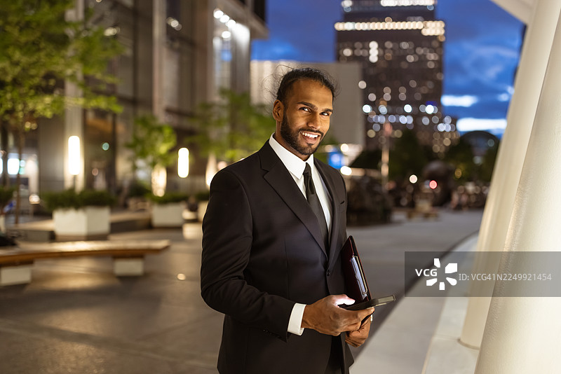 夜色中，一位商务男士在户外微笑着图片素材