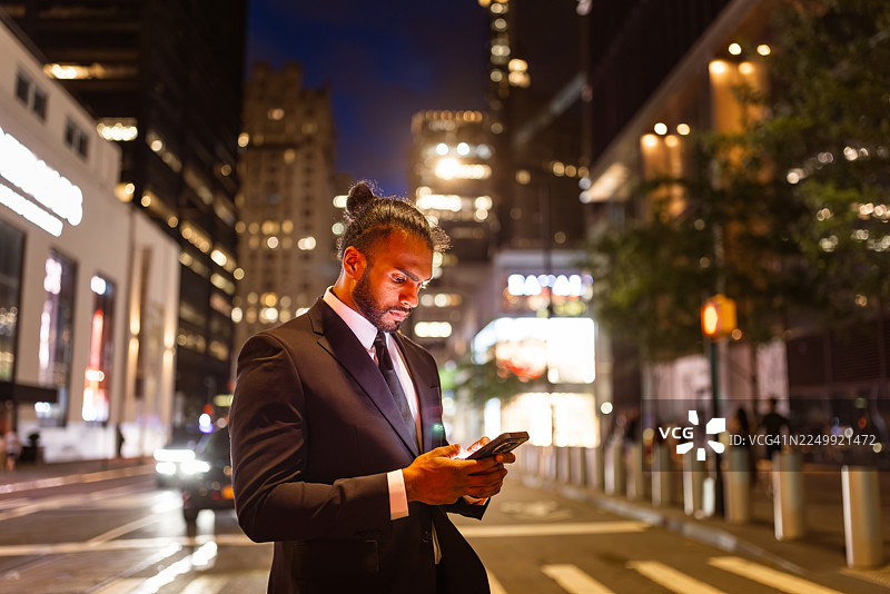 夜幕下的城市街道，一位商人正在查看手机图片素材