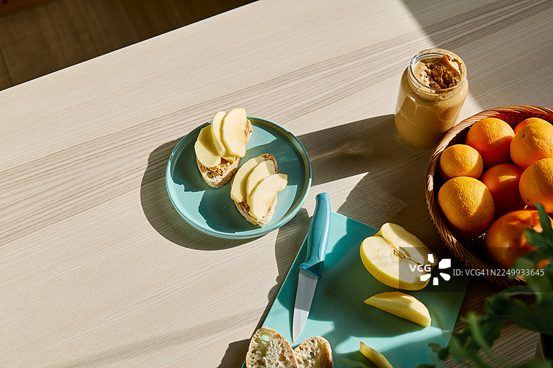 桌上放着吐司面包、花生酱和苹果片，构成健康的早餐或早午餐。图片素材