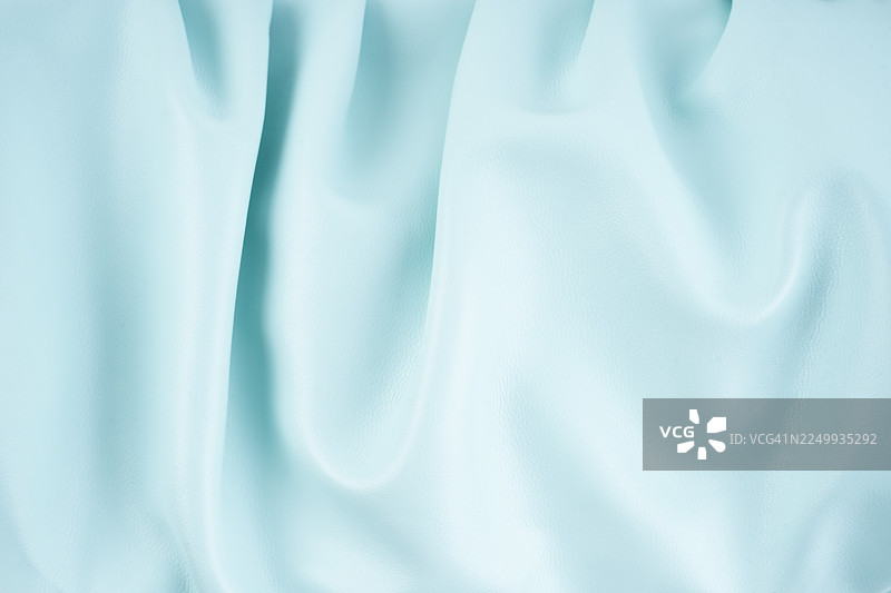 纹理细腻、有褶皱的浅绿色皮革表面特写。图片素材