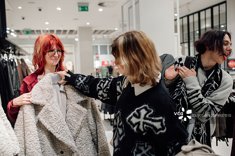 朋友们在明亮温馨的时尚店里试穿舒适的冬装图片素材