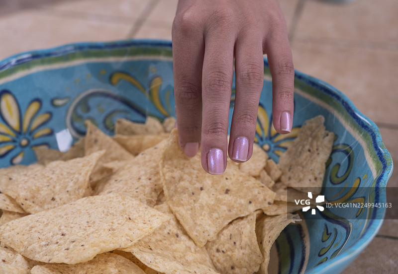 特写：女性的手从碗中拿起玉米饼脆片图片素材