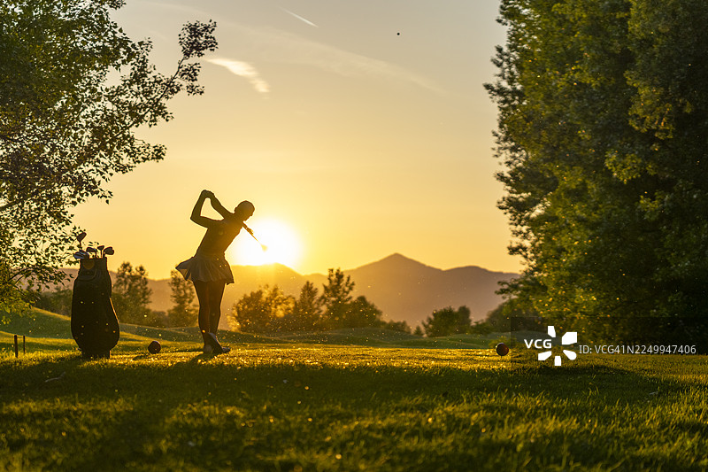 年轻的高加索女性高尔夫球手在风景优美的球场发球区享受充满活力的挥杆图片素材