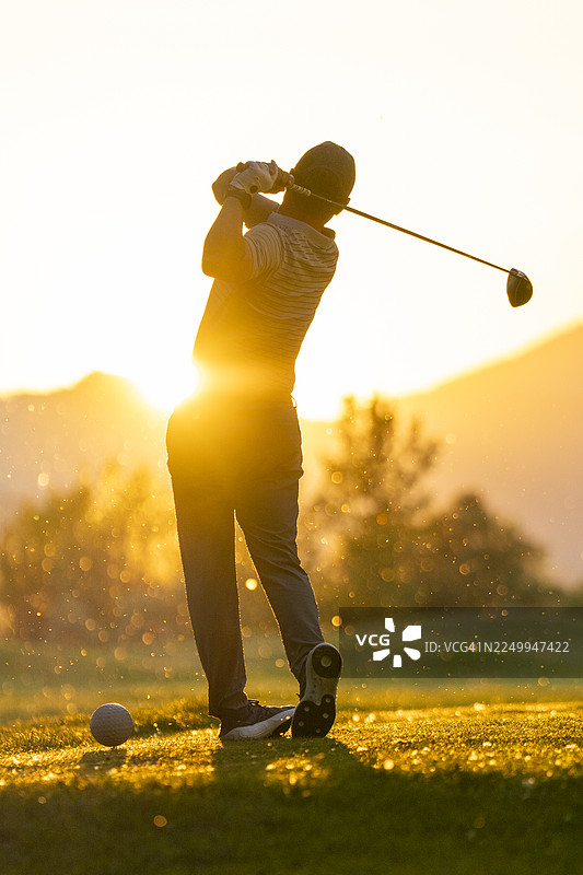 阳光明媚的球场上，一位中年白人高尔夫球手正在专注于挥杆。图片素材