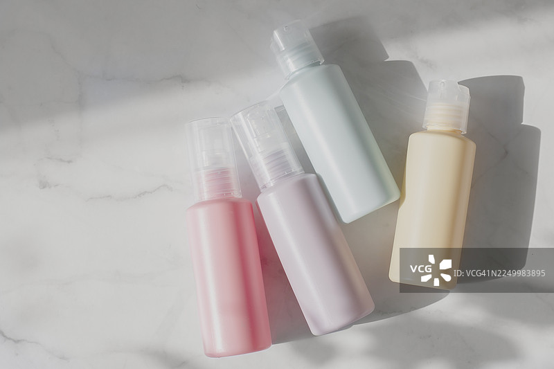 柔和的化妆品瓶子摆放在浅色大理石表面上，投下柔和的阴影。清新的现代调色板，与2026年度代表色的柔和、和谐的氛围相协调。图片素材