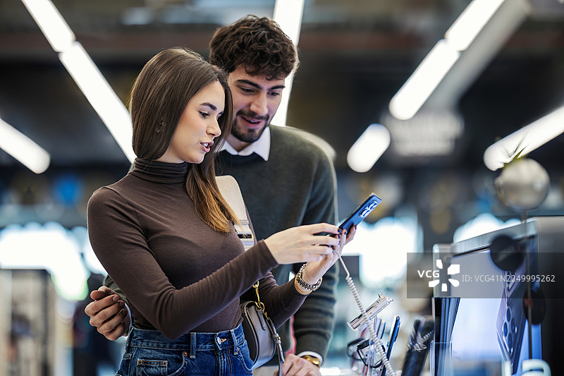 情侣在电子产品商店选购新款智能手机图片素材