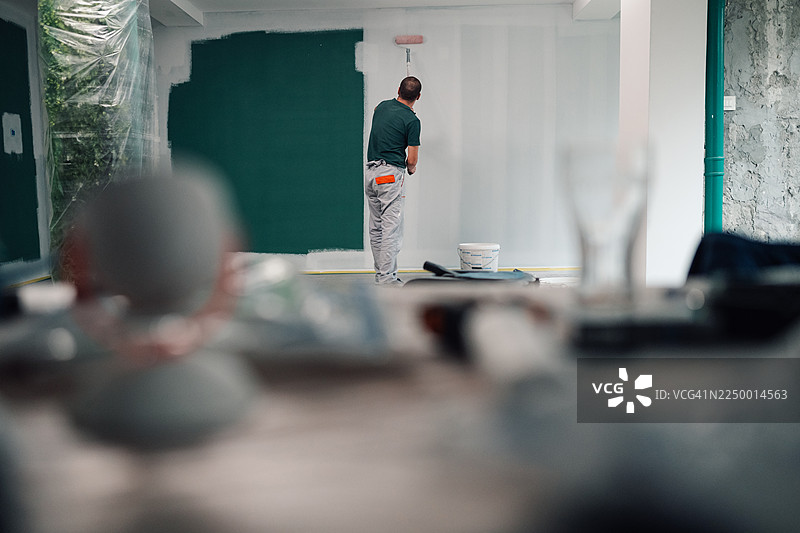 男人在房屋翻新项目中给墙壁刷成绿色图片素材