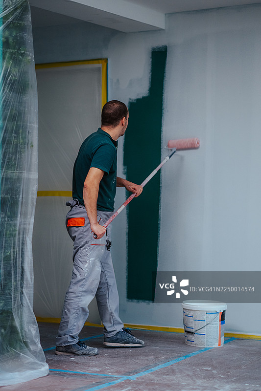 男人在翻新房屋时用滚筒粉刷墙壁图片素材