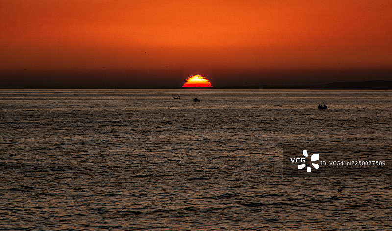 葡萄牙阿尔加维卡尔武埃罗，宁静的大西洋日落与渔船图片素材