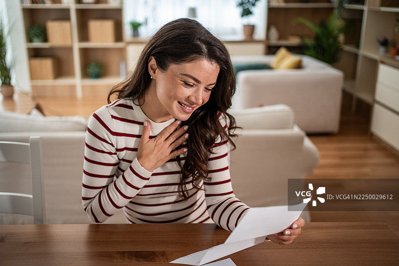 一位女士正在阅读好消息信件，感到感激和欣慰图片素材