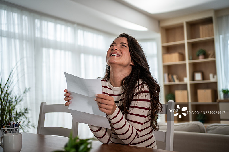 快乐的女人在家阅读好消息信件图片素材