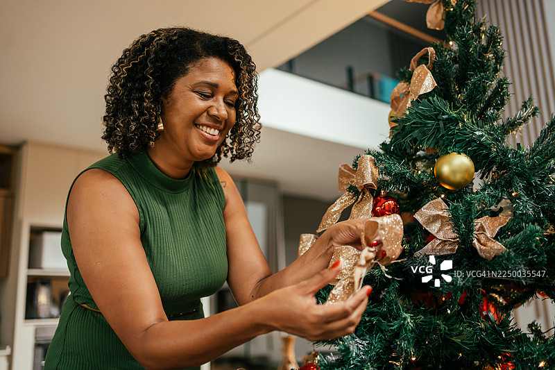 一位成熟的母亲和十几岁的女儿正在装饰圣诞树。图片素材
