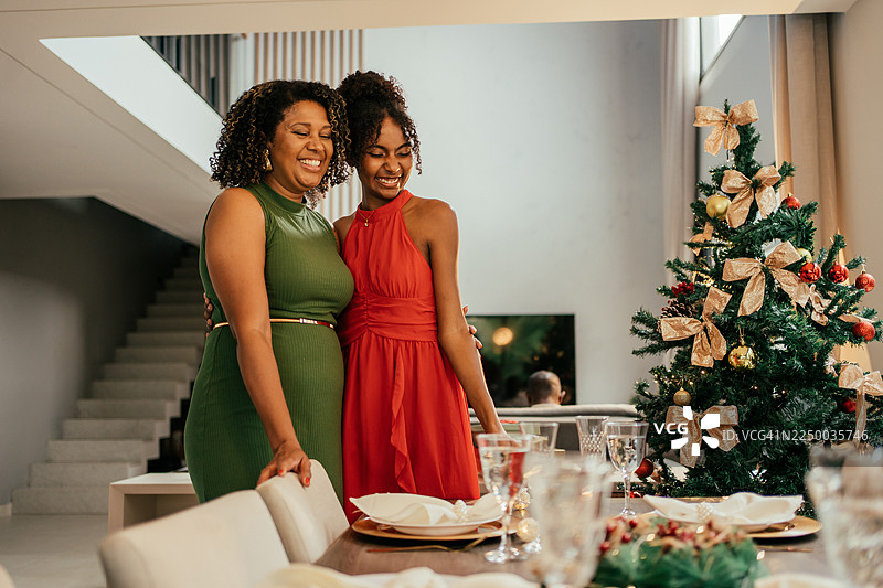 成熟的母亲和十几岁的女儿正在准备圣诞餐桌。图片素材