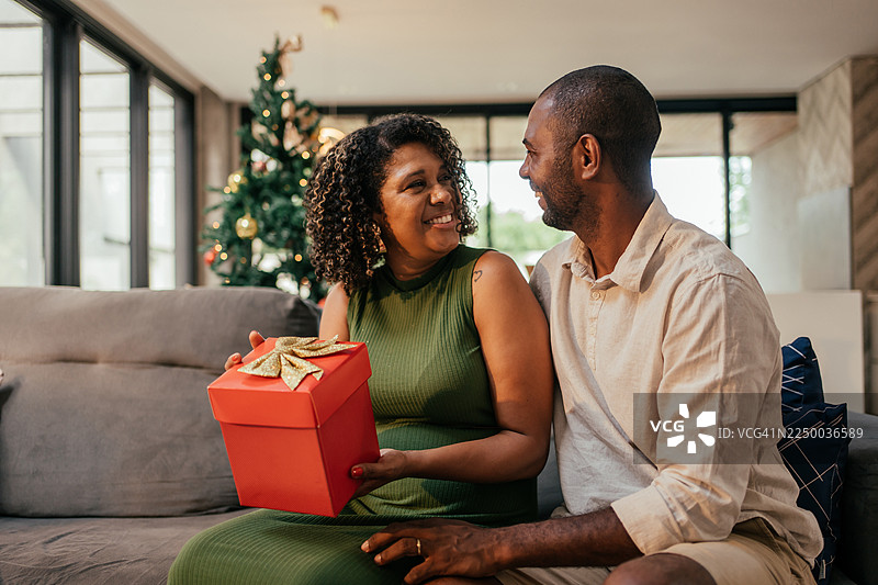 丈夫在圣诞节送妻子礼物。图片素材