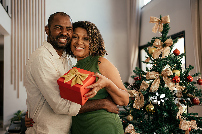 丈夫在圣诞节送给妻子一份礼物。图片素材