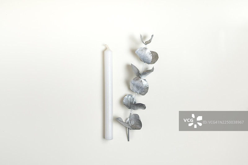 白色蜡烛和银色桉树叶，背景简约图片素材