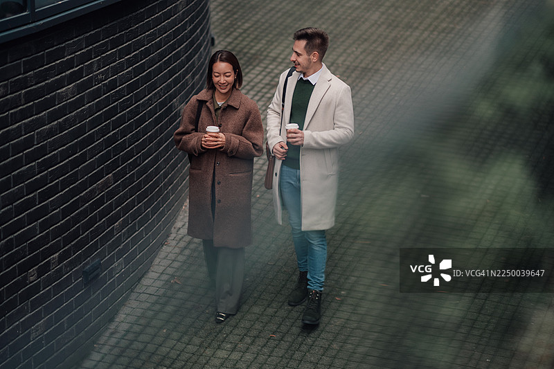 商务同事在户外边走边聊，手持咖啡图片素材