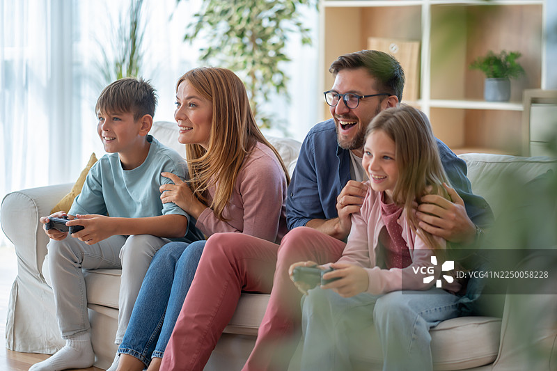 一家人在沙发上开心地玩电子游戏图片素材