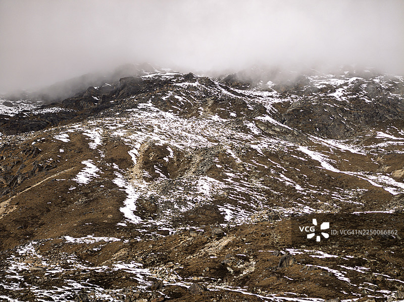 初冬时节，雾气笼罩的山坡上点缀着零星的积雪图片素材