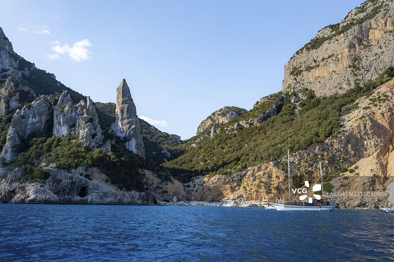 游船驶离风景如画的岩石海岸,清晨阳光下的悬崖,拉古利亚尖峰,蓝色的海和卡拉戈洛里采海滩,奥罗塞伊湾,巴乌内,撒丁岛,意大利图片素材