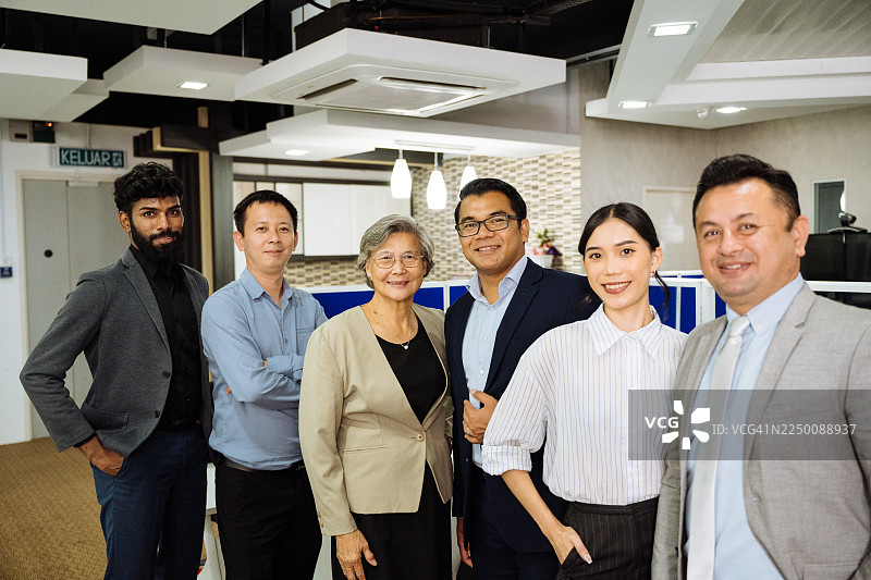 一群穿着得体的商务人士在现代办公室里合作，面带微笑看向镜头图片素材