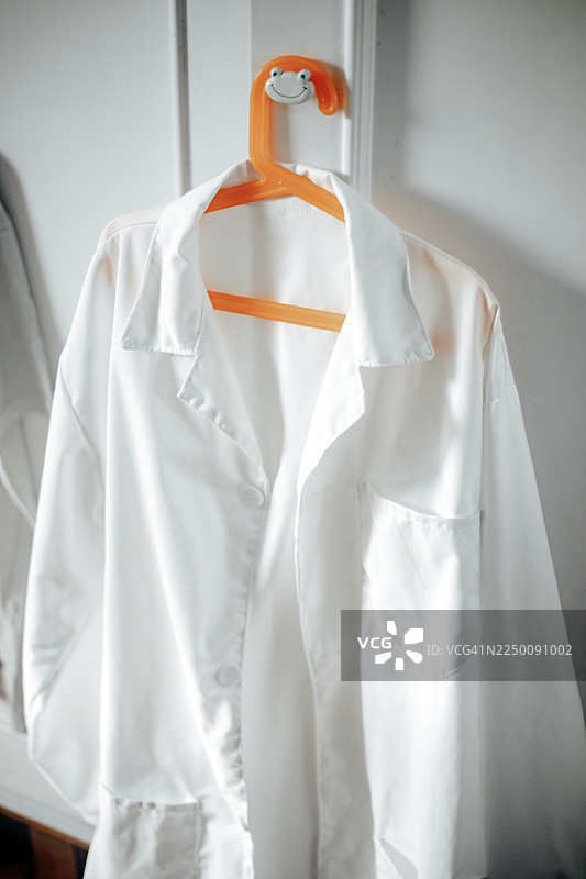 一件挂在衣架上的白色实验室外套，非常适合医学影像、干净的专业设计和医疗保健内容。图片素材