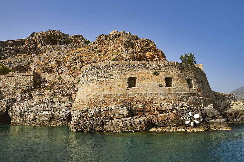希腊克里特岛东部，米拉贝罗湾，埃卢达湾，斯皮纳隆加，麻风病岛，威尼斯海滨要塞，坐落于海岸岩石上的古代要塞遗址，天空和大海清澈明朗图片素材